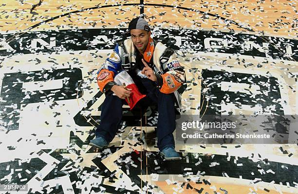 Tony Parker of the San Antonio Spurs celebrates the victory over the New Jersey Nets as he sits in street clothes at center court amidst the confetti...