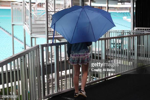Fan waits behind the stands looking out to center court during a rain delay on day 7 of the Miami Open at Hard Rock Stadium on March 22, 2024 in...