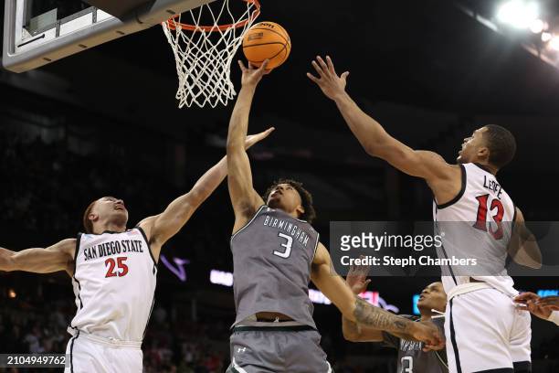 Yaxel Lendeborg of the UAB Blazers drives to the basket against Jaedon LeDee and Elijah Saunders of the San Diego State Aztecs during the second half...