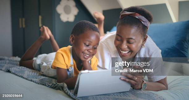 black woman, child and tablet for streaming, internet and online games on bed in bedroom, house and home for bonding. family, mother and son with technology for digital book, video and movies - multimedia learning stock pictures, royalty-free photos & images