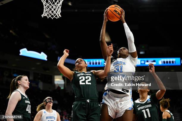 Anya Poole of the North Carolina Tar Heels catches a rebound against Moira Joiner and Jocelyn Tate of the Michigan State Spartans in the first...