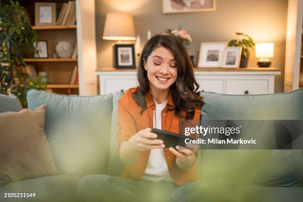 happy girl competing in smartphone video games online with friends - friends laughing at iphone video stock pictures, royalty-free photos & images