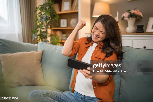 happy girl competing in smartphone video games online with friends - friends laughing at iphone video stock pictures, royalty-free photos & images