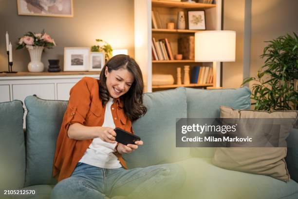 happy girl competing in smartphone video games online with friends - friends laughing at iphone video stock pictures, royalty-free photos & images