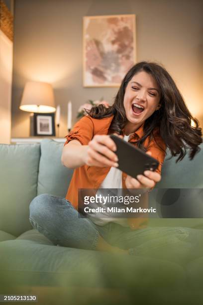 happy girl competing in smartphone video games online with friends - friends laughing at iphone video stock pictures, royalty-free photos & images