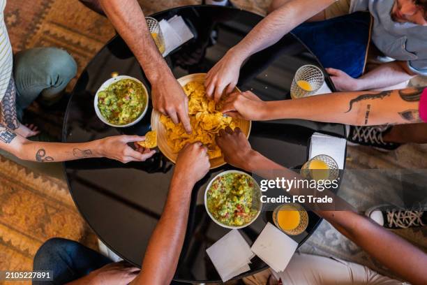 freunde essen guacamole mit nacho zu hause - guacamole stock-fotos und bilder