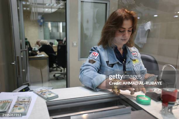 Bank teller counts money at the Central Bank of Iraq in the capital Baghdad on March 25, 2024.
