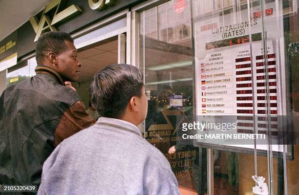 Two people look at the exchange rates posted in a commercial road in Quito 05 January 2000. Dos personas observan una tabla la cotizacion del dolar,...