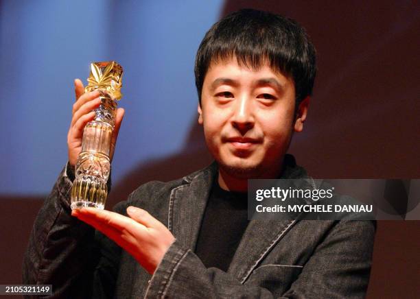 Chinese director Jia Zhang-Ke holds his trophy 13 March 2005 after winning the Lotus of the best screenplay with his film "The World" , during the...