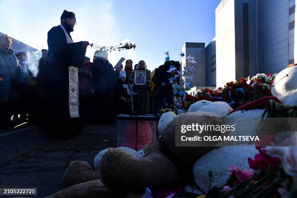 An Orthodox priest leads a service at a makeshift memorial in front of the burnt-out Crocus City Hall concert venue in Krasnogorsk, outside Moscow,...