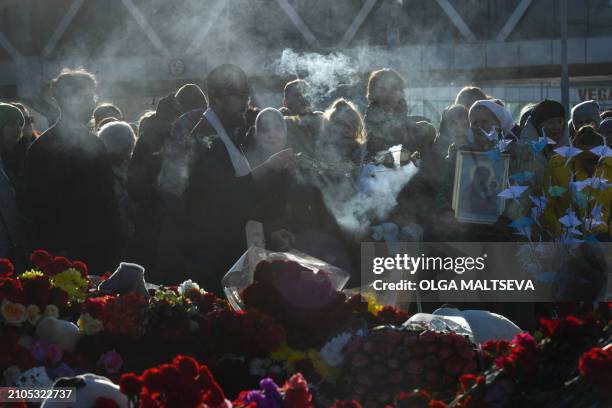 An Orthodox priest leads a service at a makeshift memorial in front of the burnt-out Crocus City Hall concert venue in Krasnogorsk, outside Moscow,...