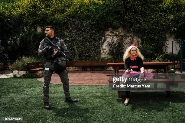 Israeli soldier watches over a young girl dressed in a costume during a parade attended by religious Israelis to celebrate the Jewish holiday of...