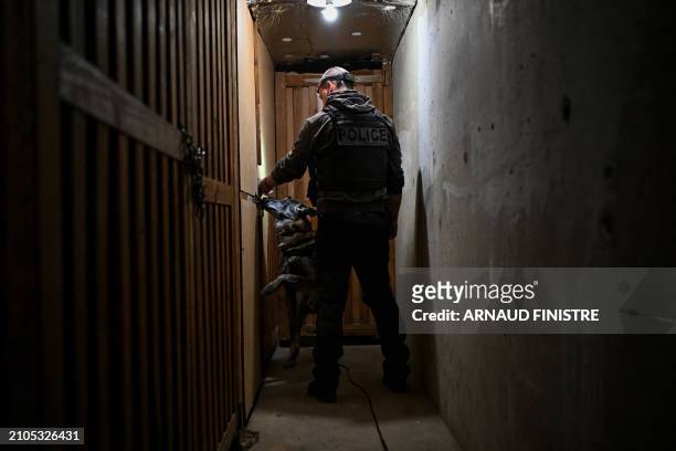Police officer from the dog squad patrols in the basement of a building in Chenove, central eastern France, on March 25 as part of the "XXL cleanup...