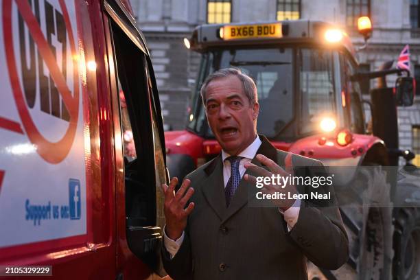 Nigel Farage speaks to the driver of a van taking part in a protest against the ULEZ charge while ahead of him farmers drive tractors near the Houses...