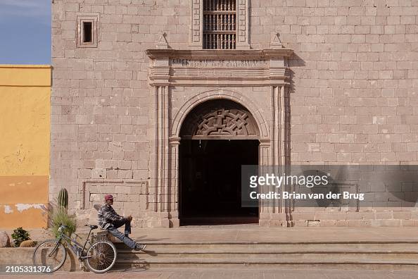 A man sits in front of Mision Loreto