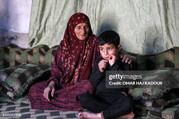 Amina al-Hamam whose son Ghazwan Hassun was detained by Hayat Tahrir al-Sham in 2019, sits with her grandson inside their tent at a camp for those...