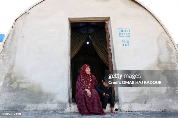 Amina al-Hamam whose son Ghazwan Hassun was detained by Hayat Tahrir al-Sham in 2019, sits with her grandson at the entrance of their tent at a camp...