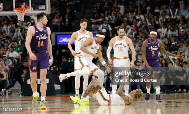 Keldon Johnson of the San Antonio Spurs rushes to help up Jeremy Sochan after he drew a charge on Drew Eubanks of the Phoenix Suns at Frost Bank...