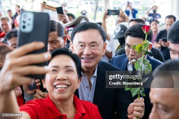 Thaksin Shinawatra, Thailand's former prime minister, center, stands for a selfie with a supporter at the Pheu Thai party headquarters in Bangkok,...