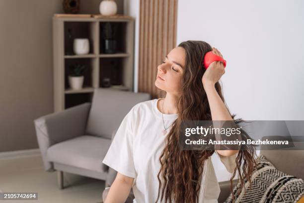 lady takes care of scalp by doing massage with scalp massager - cuero cabelludo fotografías e imágenes de stock