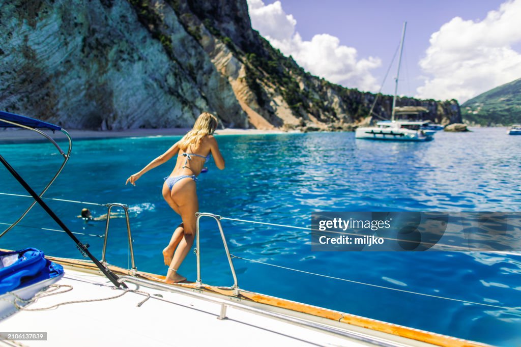 Attractive young woman jumping into the sea from a sailboat