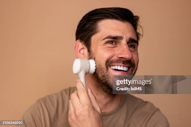 happy man using facial cleansing brush - exfoliation stock pictures, royalty-free photos & images