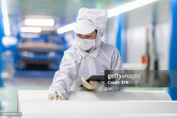 An employee produces materials used for smartphone production at a factory in Xinghua, in eastern China's Jiangsu province on March 26, 2024. / China...