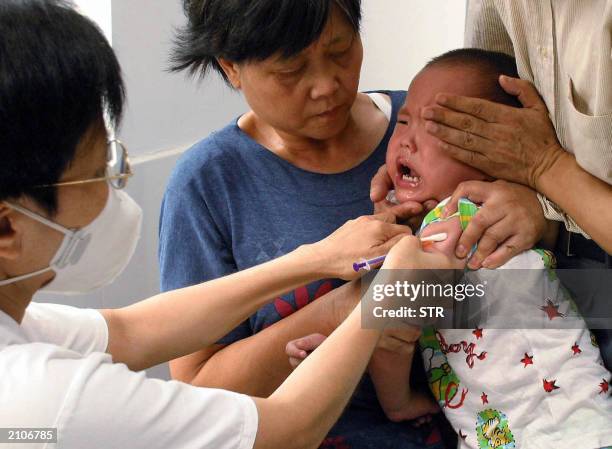 Nurse inoculates a child against Japanese encephalitis, at a local hospital in Guangzhou, southern China's Guangdong province 20 June 2003, as his...