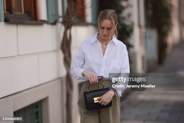 Marlies Pia Pfeifhofer seen wearing gold earrings and necklace, LAMAREL white cotton buttoned blouse shirt, Agolde beige long pants, Jimmy Choo black...