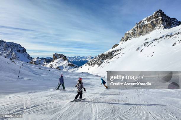 family skis down slope in italian alps - child skiing stock pictures, royalty-free photos & images