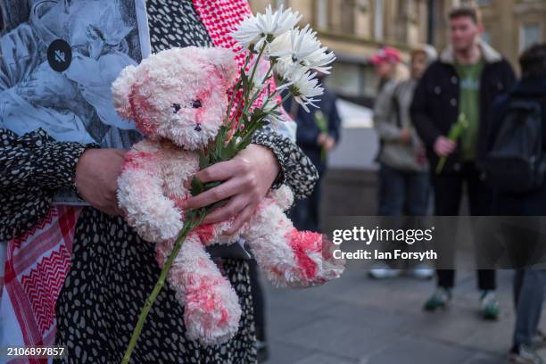 Demonstrators carry teddy bears soaked in red paint representing blood as they take part in a mass funeral procession protest to commemorate the...
