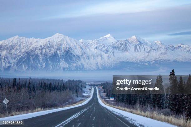 view down highway to mountains - snowy mountains canada stock pictures, royalty-free photos & images