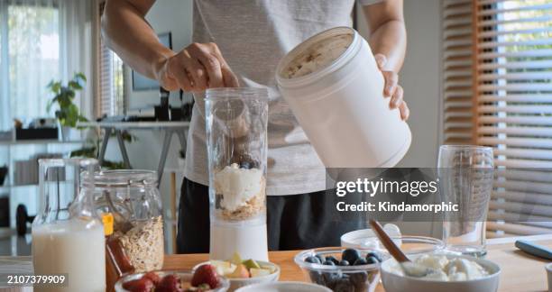 young adult asian man prepare and make protein shake drink, mixed fruit cereal juice, using blender mixer. fitness dietary activity, healthy diet lifestyle, health care nutrition concept - man workout snack stock pictures, royalty-free photos & images
