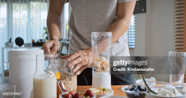 young adult asian man prepare and make protein shake drink, mixed fruit cereal juice, using blender mixer. fitness dietary activity, healthy diet lifestyle, health care nutrition concept - liquidiser stock pictures, royalty-free photos & images