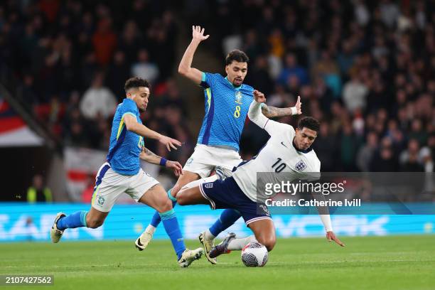 Jude Bellingham of England is challenged by Joao Gomes and Lucas Paqueta of Brazil during the international friendly match between England and Brazil...