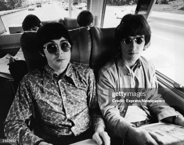 Paul McCartney and George Harrison sit next to each other on their tour bus during a Beatles American tour, c. 1966. Behind them sit Ringo Starr and...