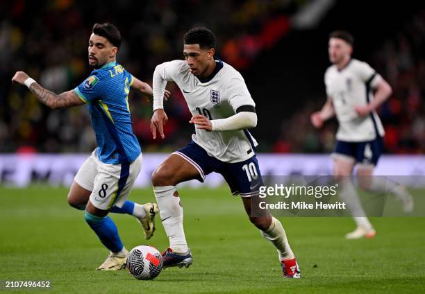 Jude Bellingham of England runs with the ball whilst under pressure from Lucas Paqueta of Brazil during the international friendly match between...