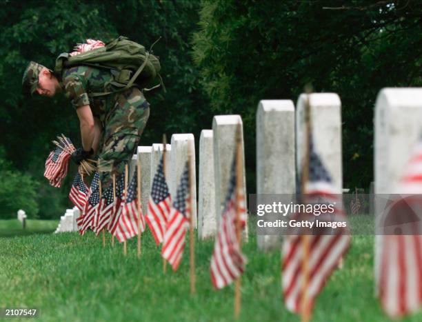 Soldier from the 5th U.S. Infantry from Fort Myers places a U.S. Flag near a gravesite at Arlington National Cemetery, Arlington, Virginia, May 25,...
