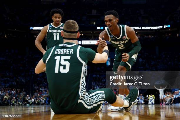 Tyson Walker of the Michigan State Spartans helps teammate Carson Cooper off the floor during the first half against the North Carolina Tar Heels in...