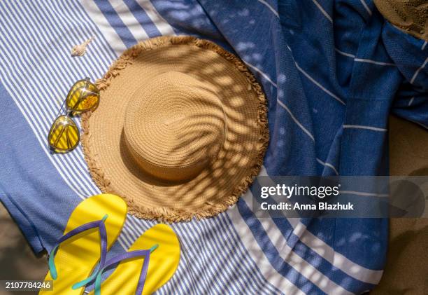 summer yellow flip-flops, sunglasses on beach towel and straw hat. summer vacation concept. view from above. bright direct sunlight. - blue white summer hat background stock pictures, royalty-free photos & images