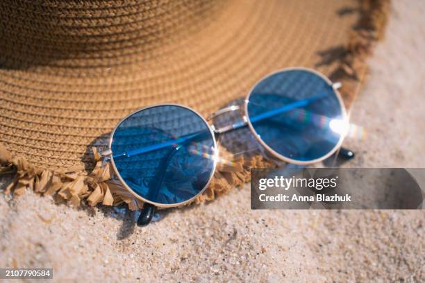 straw hat and blue sunglasses on white sand beach. summer vacation background with copy space. view from above. bright direct sunlight. - blue white summer hat background stock pictures, royalty-free photos & images
