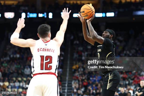 Cole of the Oakland Golden Grizzlies shoots over the defense of Michael O'Connell of the North Carolina State Wolfpack during the first half of a...