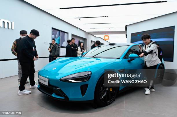 People look at a Xiaomi SU7 electric car displayed at a Xiaomi store in Beijing on March 26, 2024.