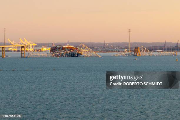 The steel frame of the Francis Scott Key Bridge sits on top of a container ship after it struck the bridge in Baltimore, Maryland, on March 26, 2024....