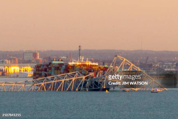 The steel frame of the Francis Scott Key Bridge sits on top of a container ship after it struck the bridge in Baltimore, Maryland, on March 26, 2024....