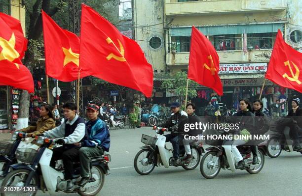 Youngsters ride motorcycles carrying communist flags and national flags during a rally held 03 February, 2000 in the centre of Hanoi to mark the 70th...