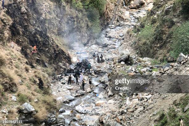 Security officials inspect the wreckage of a vehicle which was carrying Chinese nationals that plunged into a deep ravine off the mountainous...