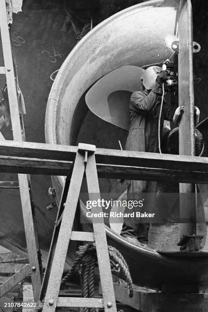 Dock worker welds the rudder of a dredger in Bailey Dry Dock in Newport, Wales, on 8th October 1984.