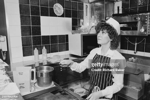 Woman flips a burger in 'Great British Burger', in Newport, Wales, on 3rd March 1985.