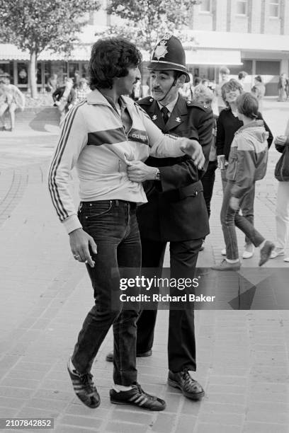 Gwent police officer takes a firm hold of a man in John Frost Square in Newport, Wales, 20th October 1984.